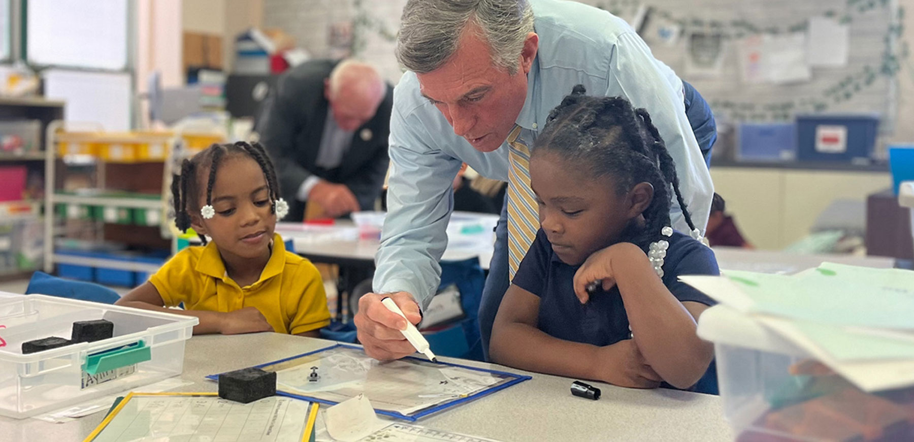 Governor John Carney at a desk with two elementary school students