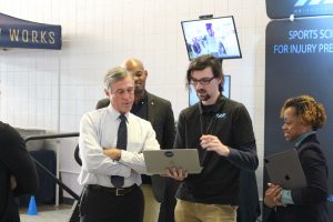 Governor Carney and the HX innovation team gather around a laptop. 